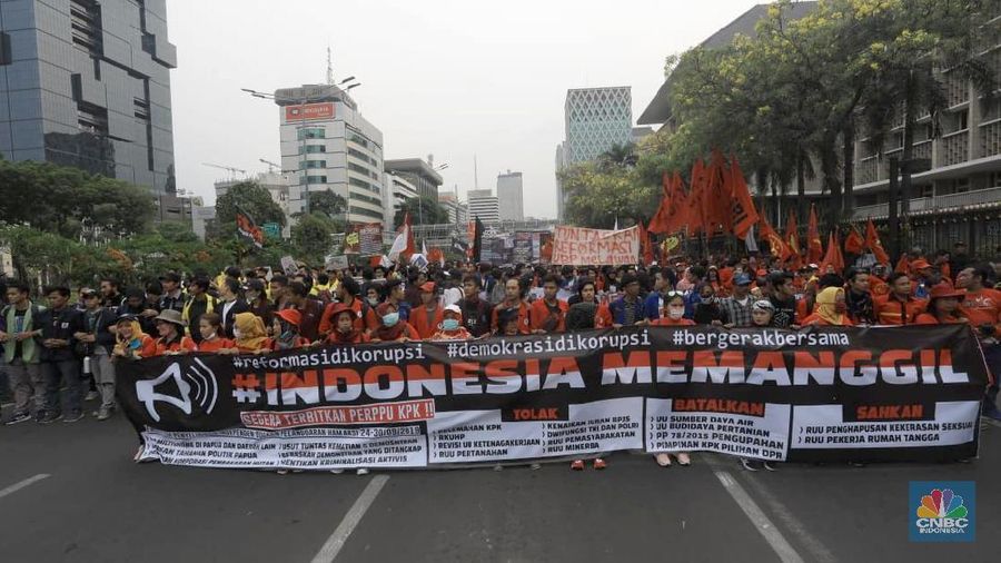 Massa membawa bendera Indonesia dan spanduk bertuliskan kritik untuk Presiden Joko Widodo dan Wakil Presiden Ma'ruf Amin.