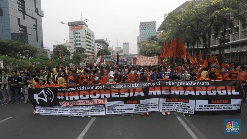 Massa membawa bendera Indonesia dan spanduk bertuliskan kritik untuk Presiden Joko Widodo dan Wakil Presiden Ma'ruf Amin.