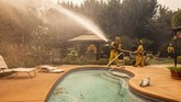 Penduduk di wilayah Brentwood, Los Angeles, harus mengungsi menghindari kebakaran hutan. (AP Photo/Ethan Swope)