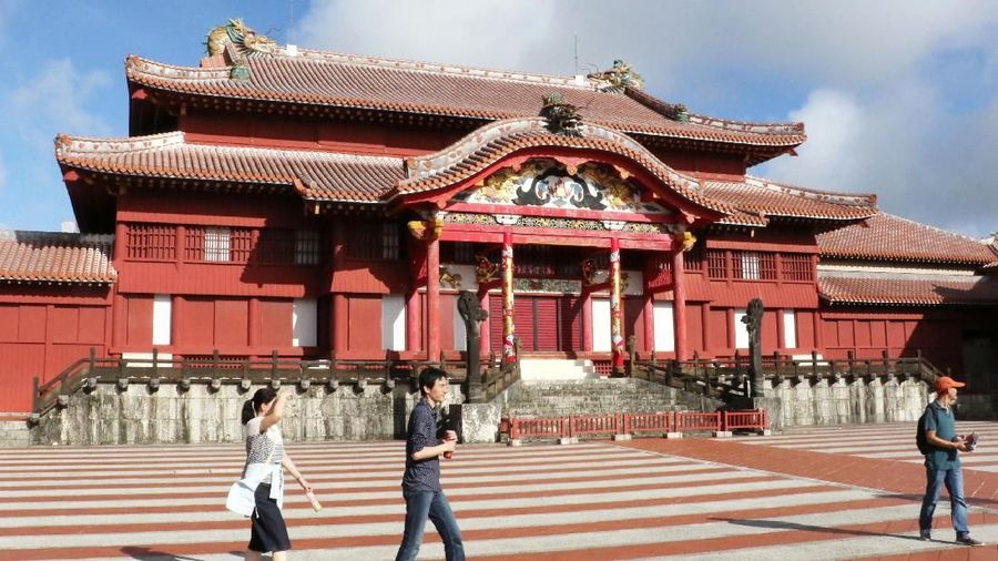 In this October 2016, photo, people walk in front of the main temple of Shuri Castle in Naha, Okinawa, southern Japan. A fire spread among structures at Shuri Castle on Thursday, Oct. 31, 2019, on Japan's southern island of Okinawa, nearly destroying the UNESCO World Heritage site. (Kyodo News via AP)