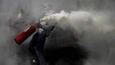 Demonstran anti-pemerintah menyemprotkan pemadam api di tengah bentrok dengan polisi di Santiago, Chile. Presiden Sebastian Pinera mengumumkan pergantian kabinet untuk meredam kerusuhan. (AP Photo/Rodrigo Abd)