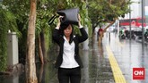 Seorang perempuan mencoba melindungi kepalanya dari curah hujan dengan menggunakan tasnya di kawaasn MH Thamrin, Jakarta, 1 November 2019. Hujan yang terjadi mendinginkan suhu Jakarta yang terpapar terik matahari beberapa bulan ini. (CNN Indonesia/ Safir Makki)