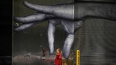 Seorang perempuan melewati mural di Manhattan, New York City, Amerika Serikat. (by Johannes EISELE / AFP)