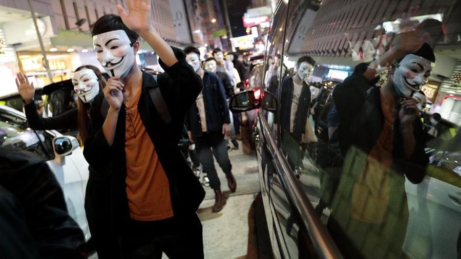 Pengunjuk rasa di Guy Fawkes mengenakan topeng dan mengangkat tangan mereka ketika mereka meneriakkan slogan-slogan selama demonstrasi di Hong Kong.