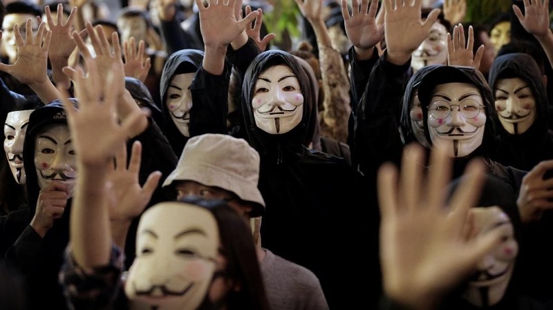 Pengunjuk rasa di Guy Fawkes mengenakan topeng dan mengangkat tangan mereka ketika mereka meneriakkan slogan-slogan selama demonstrasi di Hong Kong.