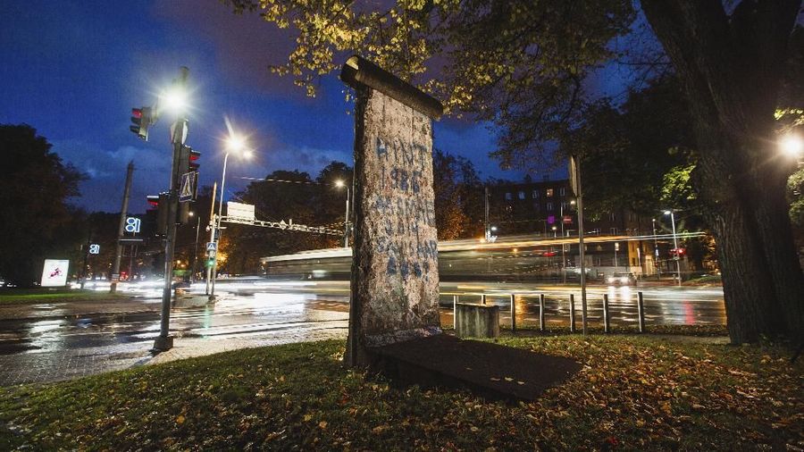 In this photo taken on Friday, Oct. 4, 2019, cars drives past a segment of the Berlin Wall installed in Tallinn, Estonia. For a barrier meant to prevent travel, chips, chunks and full segments of the 156.4 kilometer-long (97.2 mile-long) reinforced concrete Wall have done a pretty good job themselves getting around Germany and the rest of the world in the past 30 years. (AP Photo/Raul Mee)