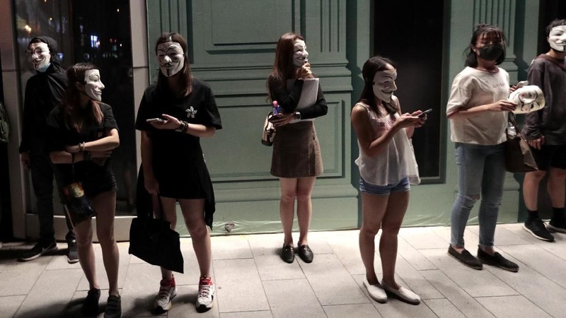 Pengunjuk rasa di Guy Fawkes mengenakan topeng dan mengangkat tangan mereka ketika mereka meneriakkan slogan-slogan selama demonstrasi di Hong Kong.