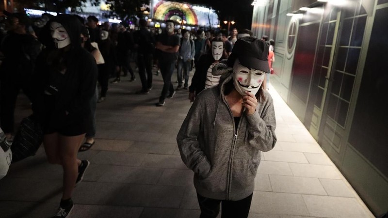 Pengunjuk rasa di Guy Fawkes mengenakan topeng dan mengangkat tangan mereka ketika mereka meneriakkan slogan-slogan selama demonstrasi di Hong Kong.
