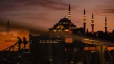 Saat matahari terbenam di distrik bersejarah Eminonu, Istanbul, orang-orang menyebrangi jembatan Halic sementara masjid Suleymaniye terlihat di latar. (Yasin AKGUL / AFP)