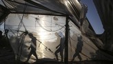 Di Khan Yunis, jalur Gaza bagian selatan, pria-pria Palestina berjalan di belakang suatu bangunan yang rusak karena serangan udara Israel. (SAID KHATIB / AFP)