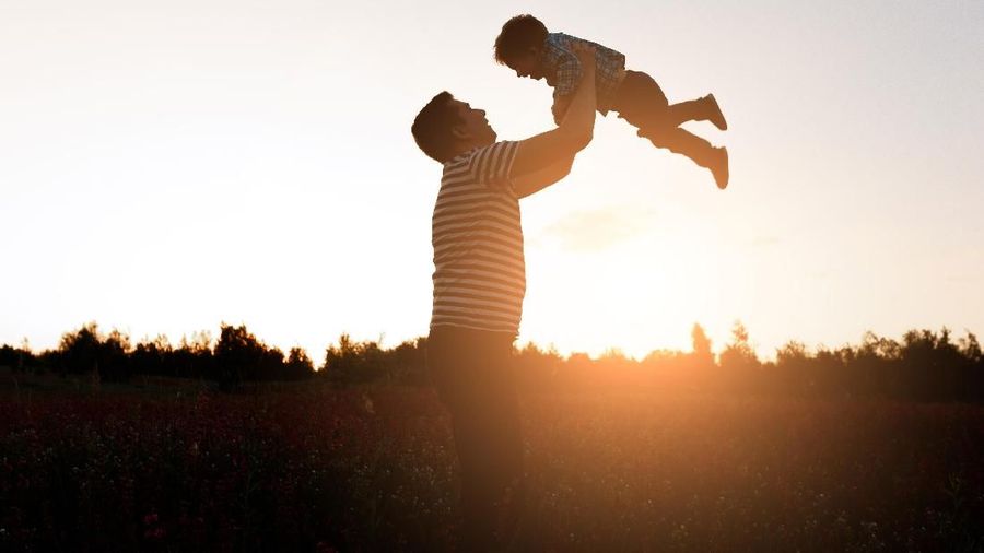 Father and son playing in the park at the sunset time. Happy family having fun outdoor.