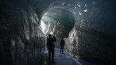 Para pekerja pun sudah menyelimuti bagian atas terowongan es yang ramai dikunjungi di daerah itu dengan terpal putih dan batu-batu besar demi melindunginya dari matahari. (Photo by MARCO BERTORELLO /AFP)