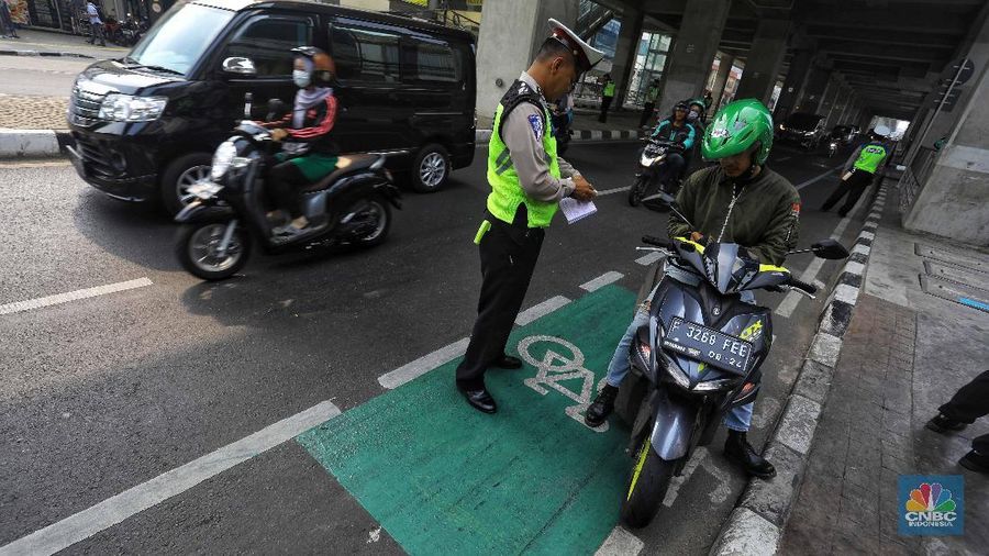  Petugas melakukan penindakan dengan sanksi tilang terhadap pengendara motor yang melintas di jalur sepeda di kawasan Fatmawati, Jakarta, Selasa (26/11/2019). 