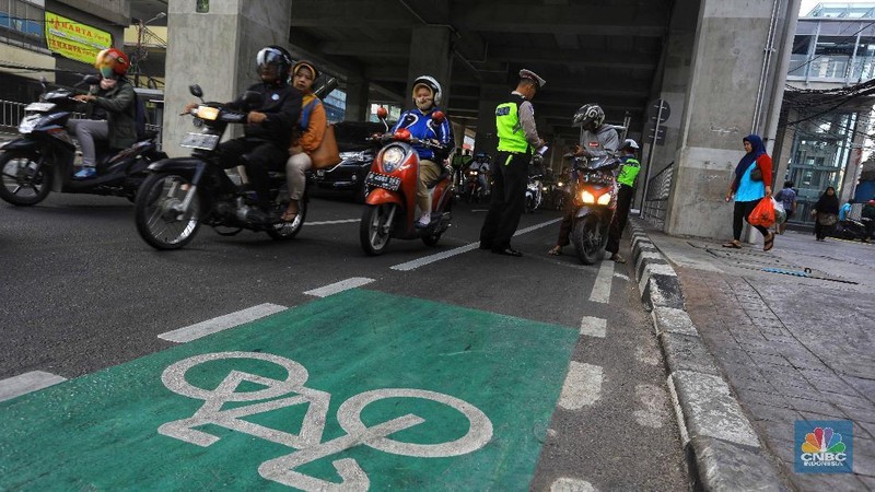  Petugas melakukan penindakan dengan sanksi tilang terhadap pengendara motor yang melintas di jalur sepeda di kawasan Fatmawati, Jakarta, Selasa (26/11/2019). 