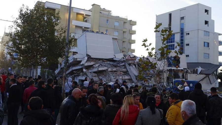 People stand near a damaged building after an earthquake in Durres, western Albania, Tuesday, Nov. 26, 2019. A strong earthquake has shaken Albania, killing at least four people, injuring 150 and collapsing buildings. (AP Photo/Hektor Pustina)