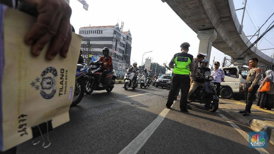  Petugas melakukan penindakan dengan sanksi tilang terhadap pengendara motor yang melintas di jalur sepeda di kawasan Fatmawati, Jakarta, Selasa (26/11/2019). 