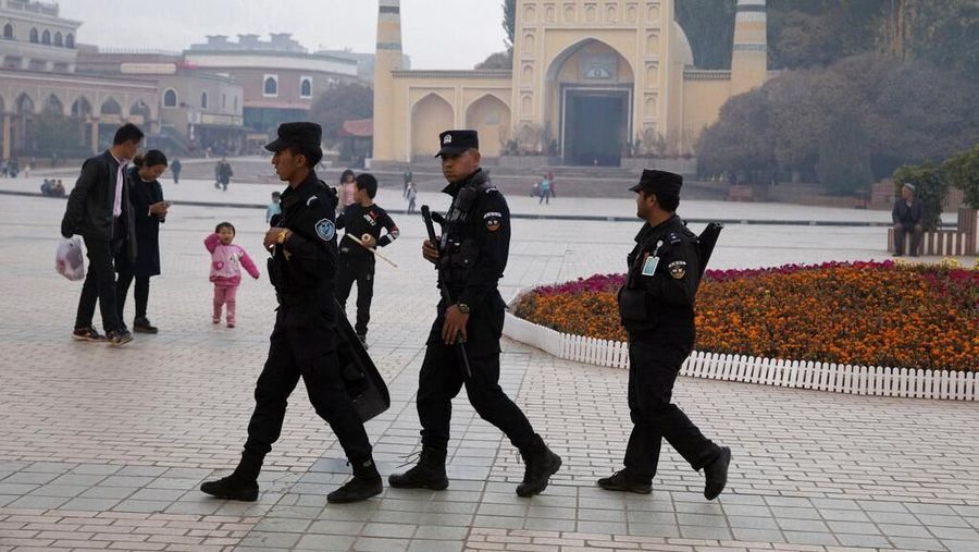 FILE - In this Nov. 4, 2017 file photo, Uighur security personnel patrol near the Id Kah Mosque in Kashgar in western China's Xinjiang region. Classified documents, leaked to a consortium of news organizations, lay out the Chinese government's deliberate strategy to lock up ethnic minorities to rewire their thoughts and even the language they speak. (AP Photo/File)