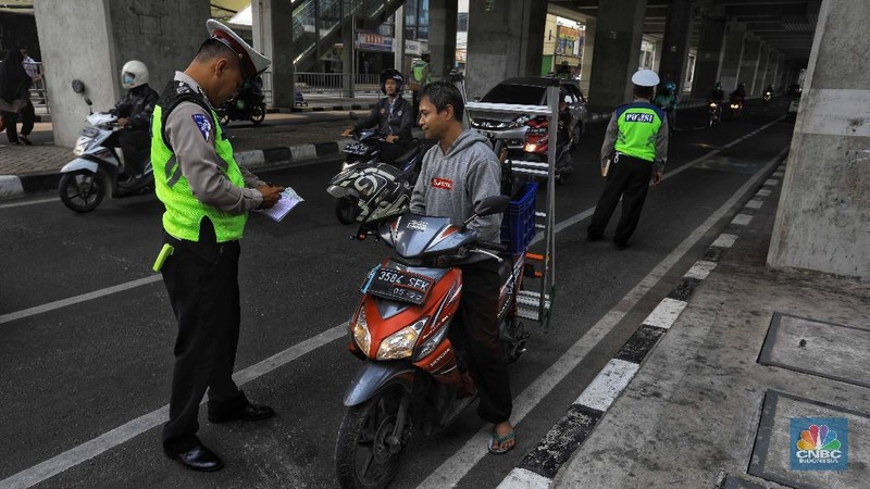  Petugas melakukan penindakan dengan sanksi tilang terhadap pengendara motor yang melintas di jalur sepeda di kawasan Fatmawati, Jakarta, Selasa (26/11/2019). 