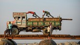 Para pekerja mendorong papan kayu yang akan digunakan untuk membangun jembatan sementara yang melintasi Sungai Gangga. Jembatan non-permanen itu akan digunakan untuk festival Magh Mela. (Photo by )