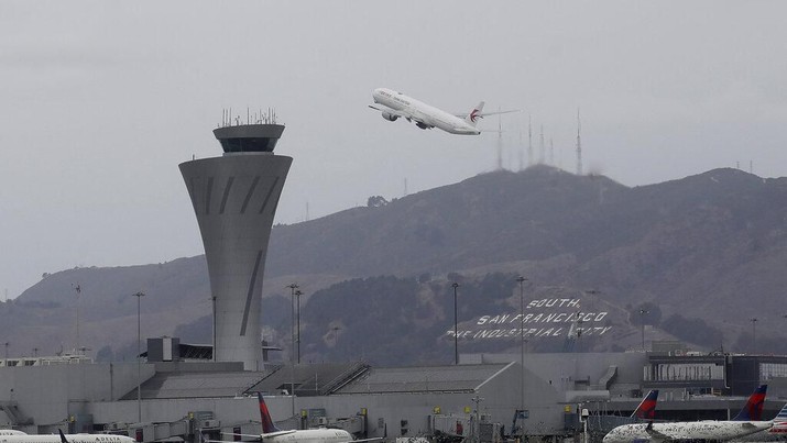 A plane takes off behind the air traffic control tower at San Francisco International Airport in San Francisco, Tuesday, Nov. 26, 2019. Northern California and southern Oregon residents are bracing for a 'bomb cyclone' that's expected at one of the busiest travel times of the year. (AP Photo/Jeff Chiu)