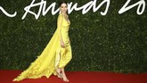 Emilia Clarke tampil dengan gaun midi berwarna kuning neon yang dipadukan dengan balutan kain panjang pada bagian lengan yang bervolume berdetail bulu karya Schiaparelli. (Photo by Joel C Ryan/Invision/AP)