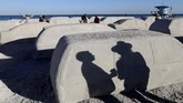 Warga tengah berjalan di 'mobil pasir' hasil perupa Leandro Erlich di Pantai Miami, Argentina pada Selasa (3/12) untuk menarik perhatian isu perubahan iklim dan kenaikan air laut. (AP Photo/Lynne Sladky)