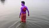 Seorang sukarelawan menceburkan dirinya ke sungai untuk membasuh cat yang ada di tubuhnya terkait dengan peringatah Hari AIDS Dunia pada Kolkata, Sabtu (30/11). (Photo by Dibyangshu SARKAR / AFP)