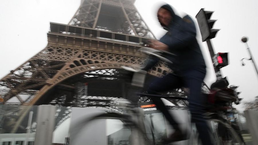 A woman walks her dog on the empty Champs Elysees avenue, with the Arc de Triomphe in background, in Paris, Thursday, Dec. 5, 2019. The Eiffel Tower shut down Thursday, France's vaunted high-speed trains stood still and teachers walked off the job as unions launched nationwide strikes and protests over the government's plan to overhaul the retirement system. (AP Photo/Francois Mori)