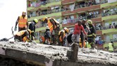 Masyarakat yang penasaran berdiri di sekitar bangunan enam lantai yang roboh di Nairobi saat tim SAR melakukan pencarian korban, Jumat (6/12). (AP Photo/Khalil Senosi)