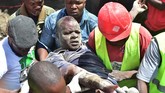 Tim SAR membopong seorang laki-laki yang terluka akibat runtuhan bangunan enam lantai yang terjadi di Kenya, Jumat (6/12).(AFP/Simon MAINA)