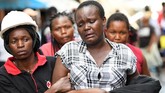 Seorang pekerja medis mendampingi seorang wanita yang sedang menangis di sekitar reruntuhan bangunan enam lantai yang roboh di Kenya, Jumat (6/12). (AFP/Simon MAINA)