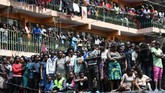 Masyarakat yang penasaran berdiri di sekitar bangunan enam lantai yang roboh di Nairobi saat tim SAR melakukan pencarian korban, Jumat (6/12). (AFP/SIMON MAINA)