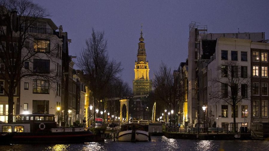 Amsterdam's Zuiderkerk, or South Church, is illuminated in Amsterdam, Netherlands, Friday, Dec. 8, 2017. Hordes of tourists are derailing daily life in parts of historic Amsterdam as visitors clog the city's narrow streets and alleys and stores catering only to tourists edge out shops for locals. (AP Photo/Peter Dejong)