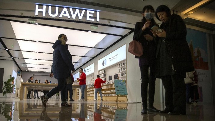 In this Nov. 20, 2019, photo, people stand outside of a Huawei store at a shopping mall in Beijing. The founder of Huawei says the Chinese tech giant is moving its U.S. research center to Canada due to American restrictions on its activities. (AP Photo/Mark Schiefelbein)