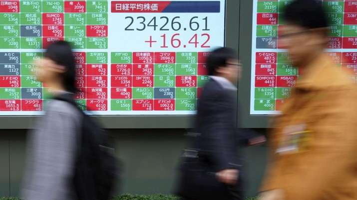 People walk past an electronic stock board showing Japan's Nikkei 225 index at a securities firm in Tokyo Wednesday, Dec. 11, 2019. Asian stock markets have risen following a report President Donald Trump plans to delay a tariff hike on Chinese goods. (AP Photo/Eugene Hoshiko)