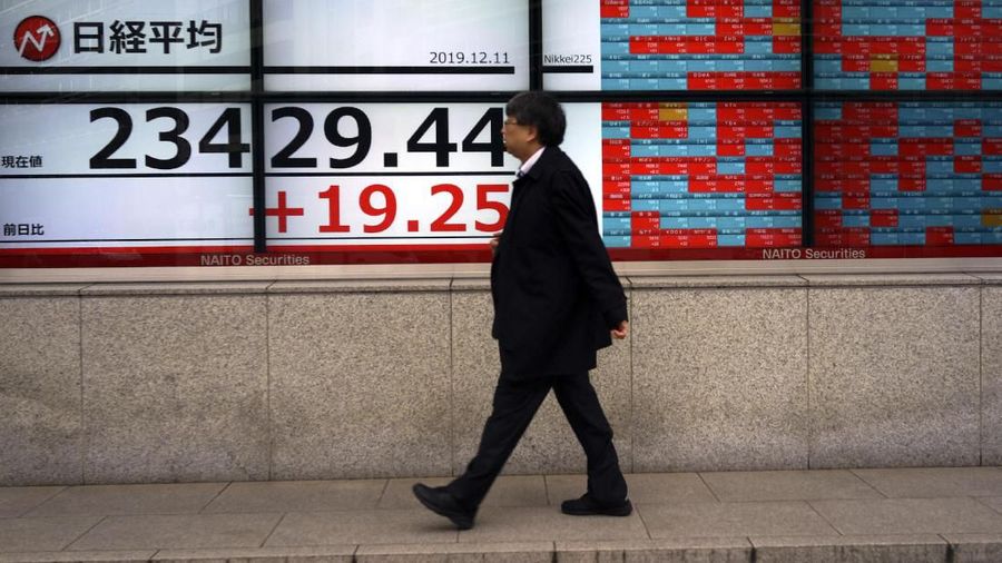 A man walks past an electronic stock board showing Japan's Nikkei 225 index at a securities firm in Tokyo Wednesday, Dec. 11, 2019. Asian stock markets have risen following a report President Donald Trump plans to delay a tariff hike on Chinese goods. (AP Photo/Eugene Hoshiko)