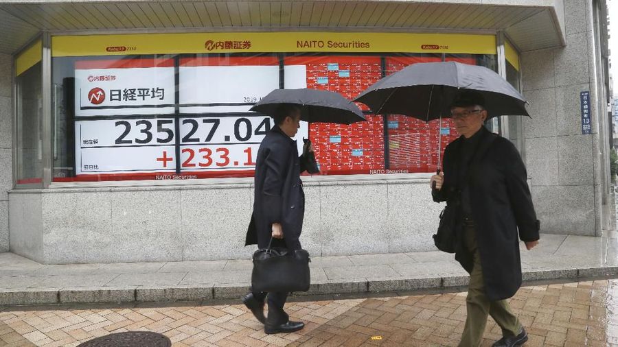 People walk by an electronic stock board of a securities firm in Tokyo, Monday, Dec. 2, 2019. Asian stock markets have risen after Chinese factory activity improved ahead of a possible U.S. tariff hike on Chinese imports. Benchmarks in Shanghai, Tokyo and Hong Kong advanced.  (AP Photo/Koji Sasahara)
