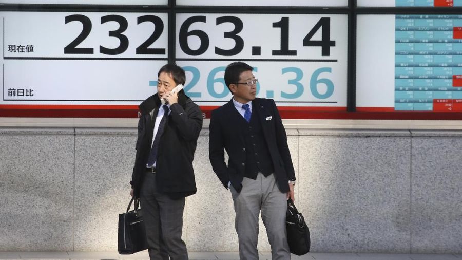 People stand in front of an electronic stock board of a securities firm in Tokyo, Tuesday, Dec. 3, 2019. Asian shares slipped Tuesday, following a drop on Wall Street amid pessimism over U.S.-China trade tensions. (AP Photo/Koji Sasahara)