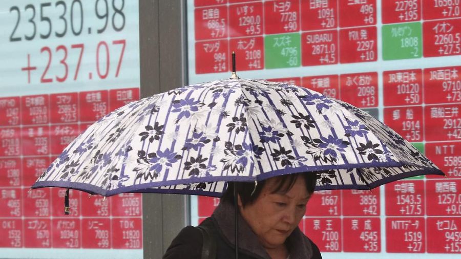 A woman walks by an electronic stock board of a securities firm in Tokyo, Monday, Dec. 2, 2019. Asian stock markets have risen after Chinese factory activity improved ahead of a possible U.S. tariff hike on Chinese imports. Benchmarks in Shanghai, Tokyo and Hong Kong advanced. (AP Photo/Koji Sasahara)