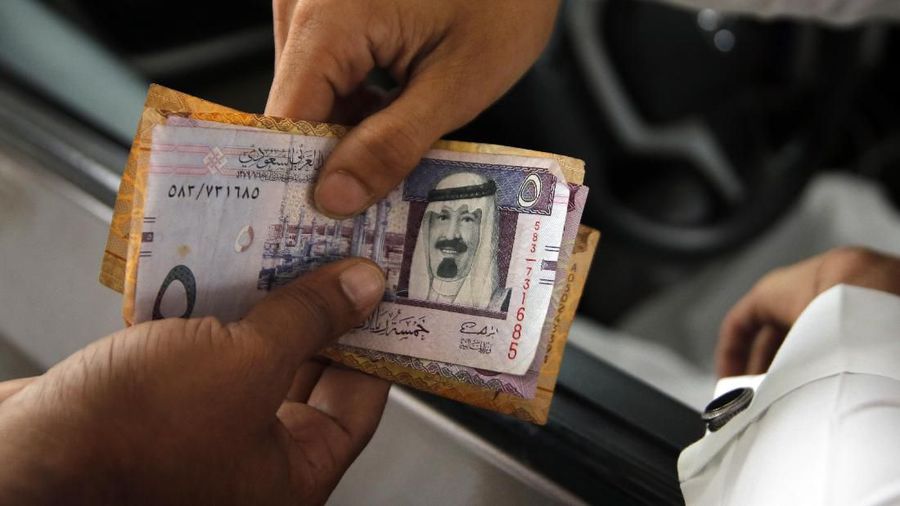 A station attendant returns Saudi Riyal cash to customer after he refuels his car at a gas station in Riyadh, Saudi Arabia, Monday, Dec. 9, 2019. (AP Photo/Amr Nabil)