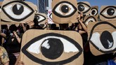 Dalam suatu aksi protes pada pemerintahan Pinera di Santiago, Chile, demostran memegang papan bergambar mata -- merujuk pada peluru polisi yang melukai mata demonstran. (Photo by HECTOR RETAMAL / AFP)