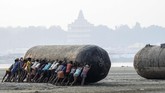 Para pekerja India mendorong buoy atau tongkang di pinggiran sungai Gangga. Mereka sedang membangun jembatang apung untuk perayaan festival Magh Mela di Allahabad. (SANJAY KANOJIA/AFP)