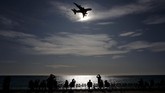 Orang-orang melihat pesawat A380 yang terbang menuju bandara di kota Nice, Perancis. (VALERY HACHE/AFP)