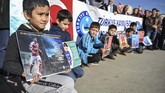 Bocah muslim Uighur memegang poster dukungan untuk Mesut Ozil. Mantan pemain Real Madrid itu dikecam netizen China karena mengungkapkan dukungan untuk etnis muslim Uighur. (Ozan KOSE / AFP)