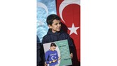 Bocah pendukug muslim Uighur membawa poster gambar Mesut Ozil. Dalam sebuah cuitan Ozil mengkritik negara-negara Islam yang dianggap tidak peduli terhadap nasib etnis Uighur. (Ozan KOSE / AFP)