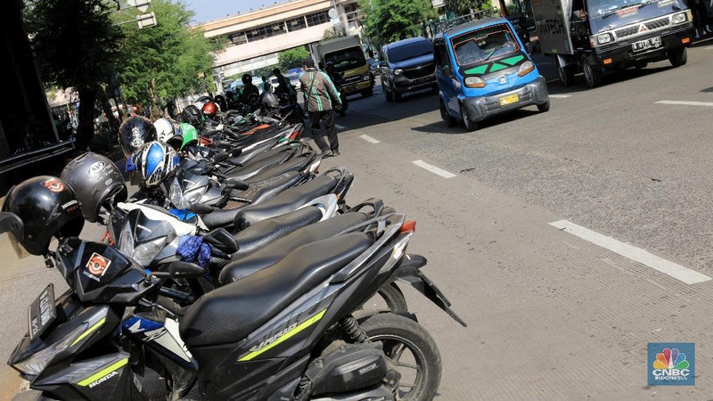 Pengemudi ojol memarkirkan motornya di tepi trotoar jalur Transjakarta di kawasan Mangga Dua.