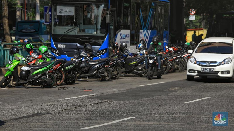 Pengemudi ojol memarkirkan motornya di tepi trotoar jalur Transjakarta di kawasan Mangga Dua.