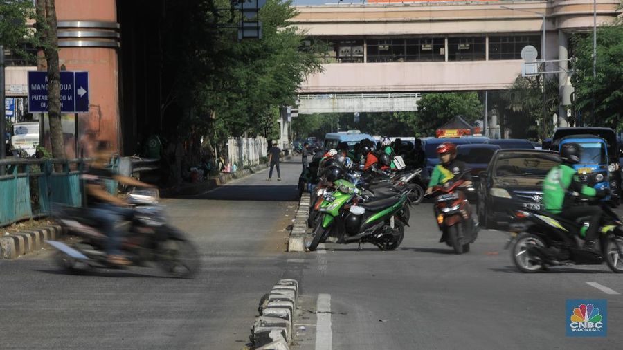 Pengemudi ojol memarkirkan motornya di tepi trotoar jalur Transjakarta di kawasan Mangga Dua.