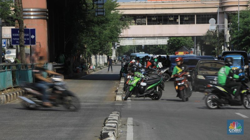 Pengemudi ojol memarkirkan motornya di tepi trotoar jalur Transjakarta di kawasan Mangga Dua.