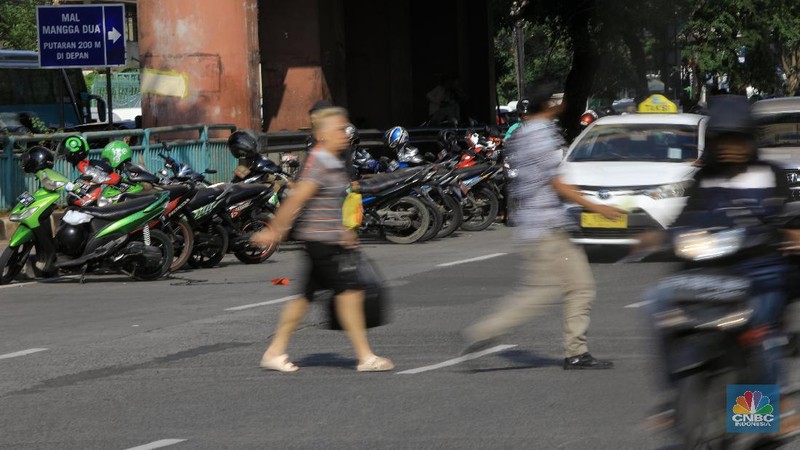 Pengemudi ojol memarkirkan motornya di tepi trotoar jalur Transjakarta di kawasan Mangga Dua.